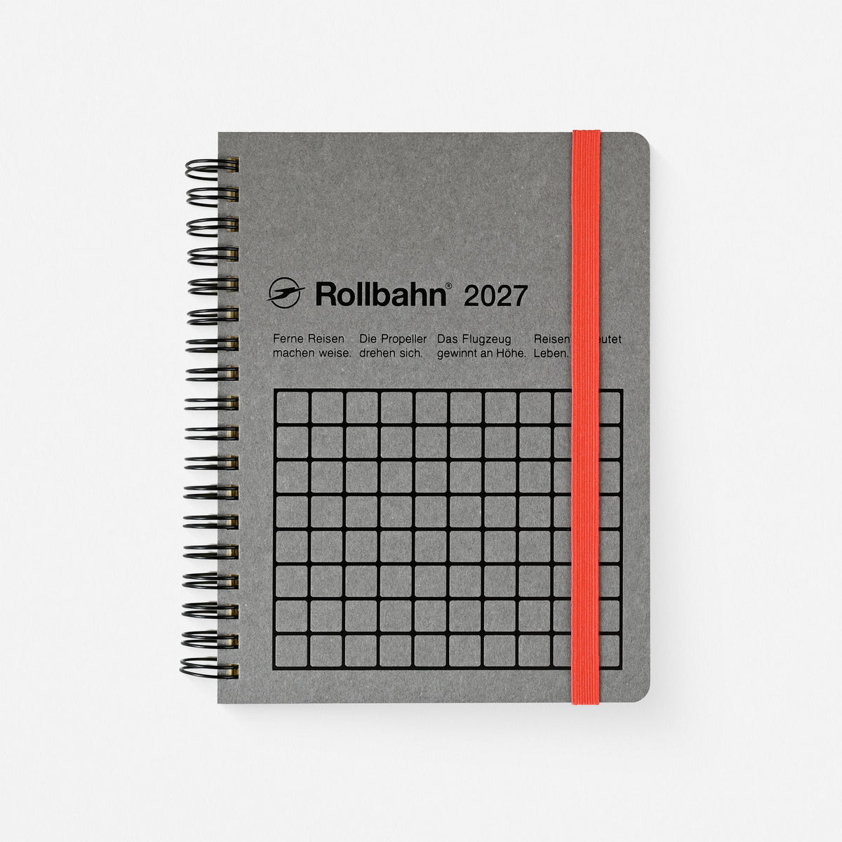 A gray spiral-bound 2027 Rollbahn planner  with a black wire coil, featuring the Rollbahn 2027 logo and a black grid on the cover, secured with a bright orange-red elastic band,  