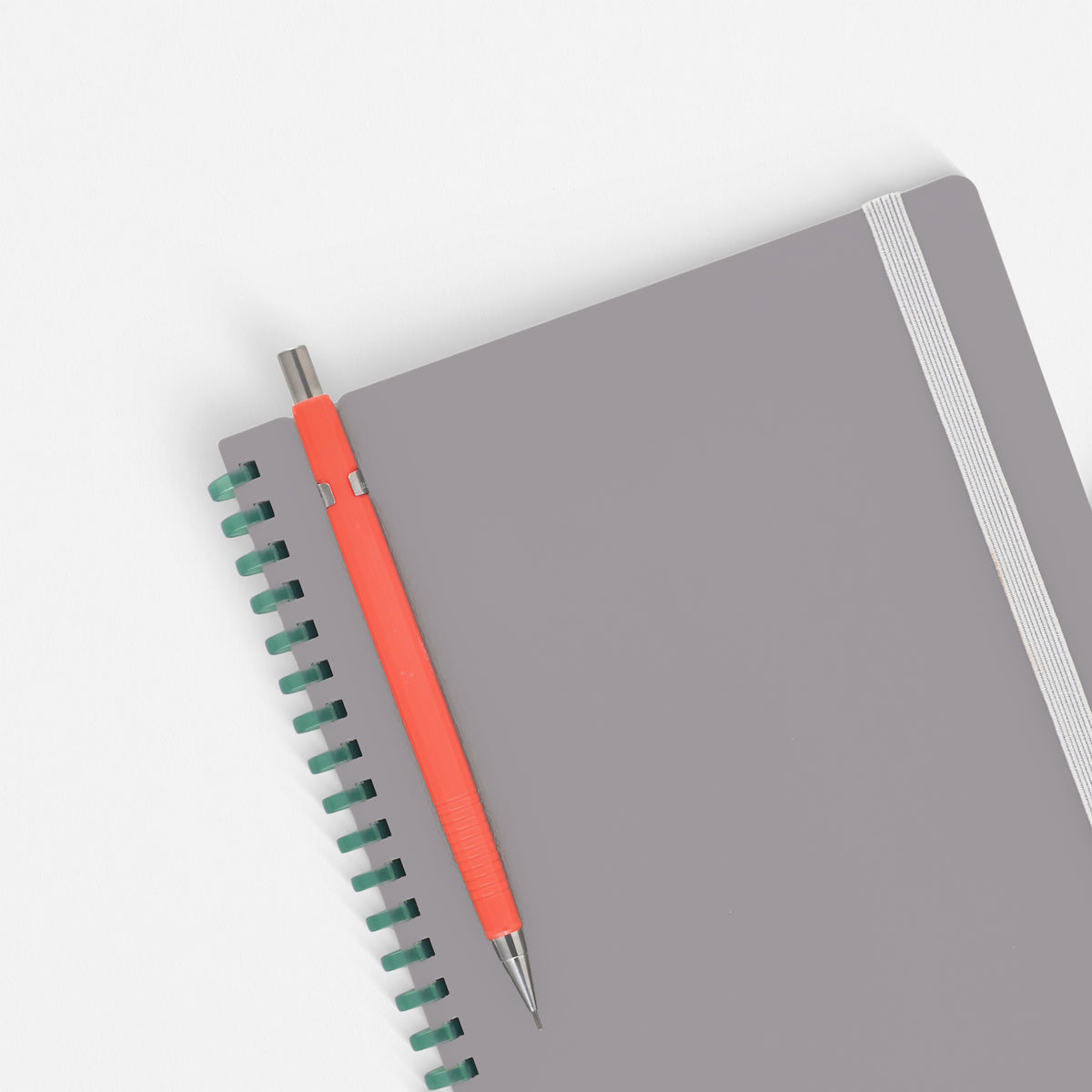 Kokuyo Sooofa Soft Ring Notebook in grey with a pen clipped in the notch at the top of the cover
